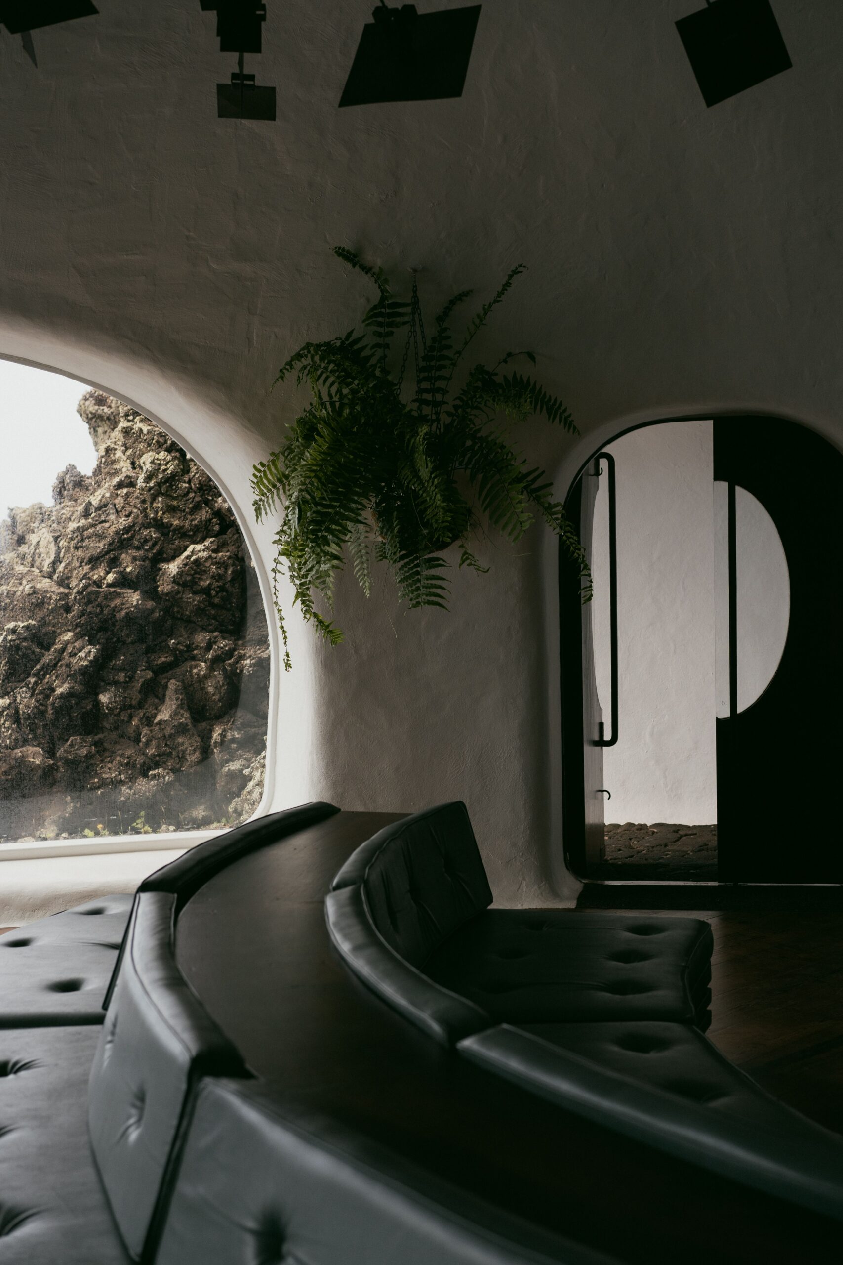 فضای داخلی با مبل منحنی و بازشوی قوسی در کنار دیوار سنگی